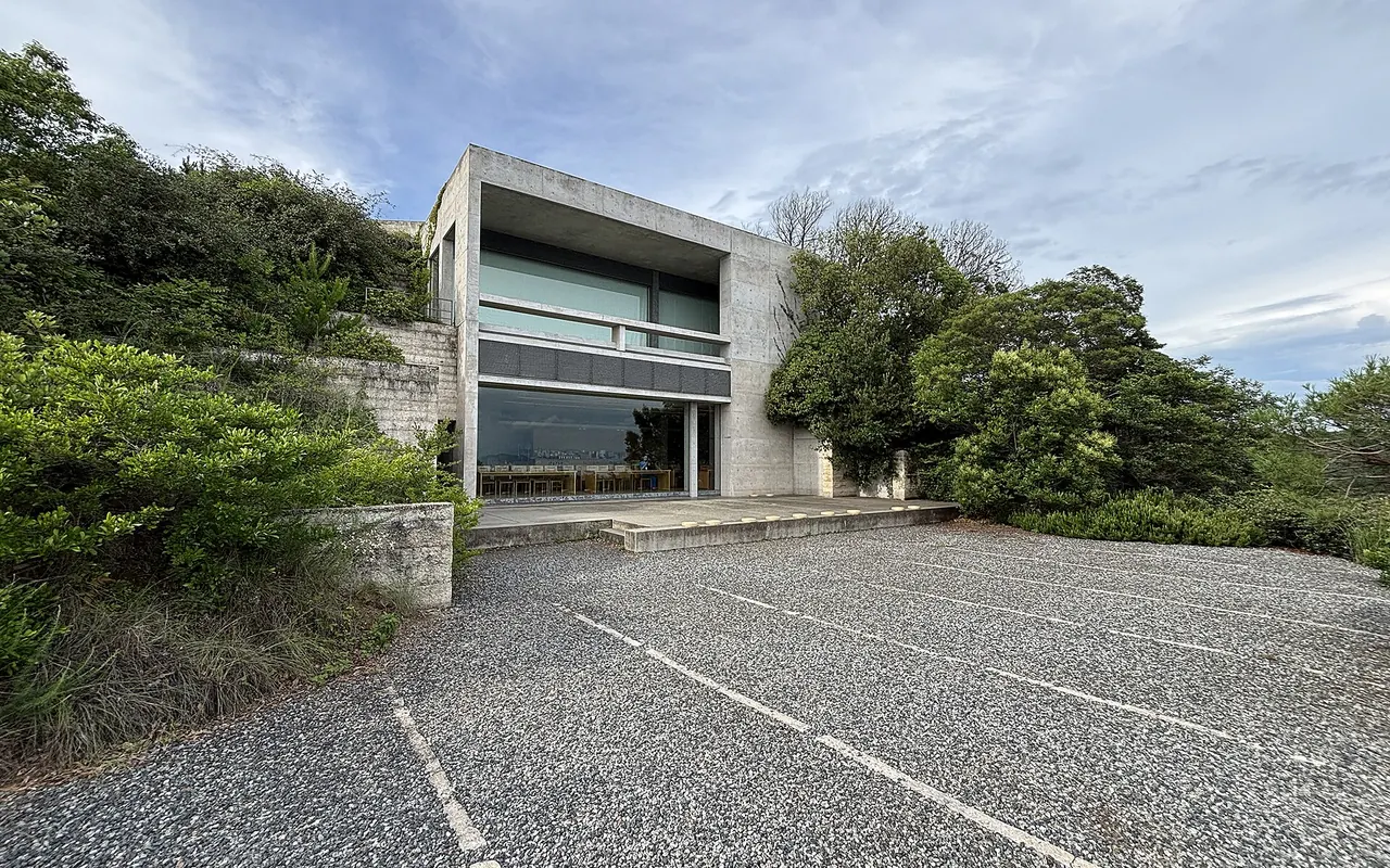 Kahle Betonwände und ein glasfrontiger Bau des Chichu Art Museum, eingebettet in einen grünen Hang